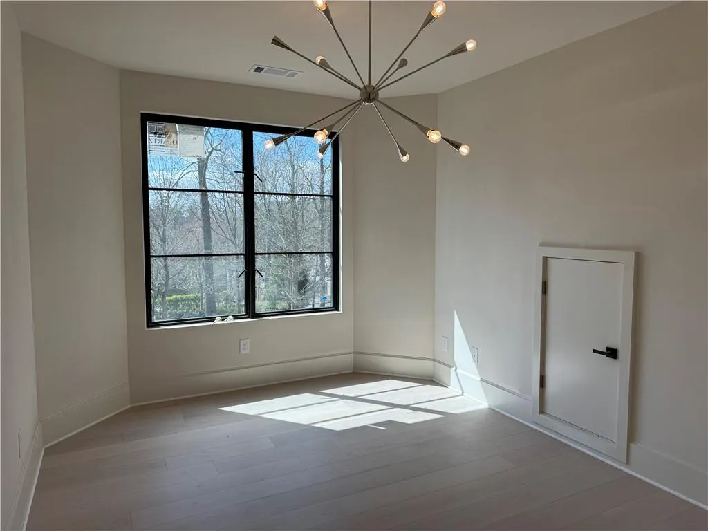 Spare room featuring suspended lighting and light wood-style flooring