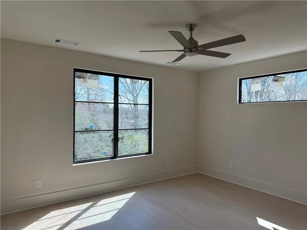 Spare room featuring light wood finished floors, healthy amount of natural light, and ceiling fan