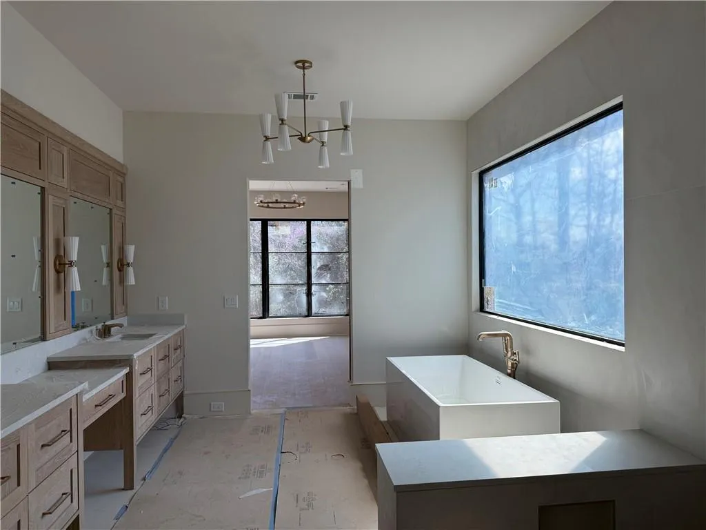 Full bathroom with suspended lighting, a soaking tub, and vanity