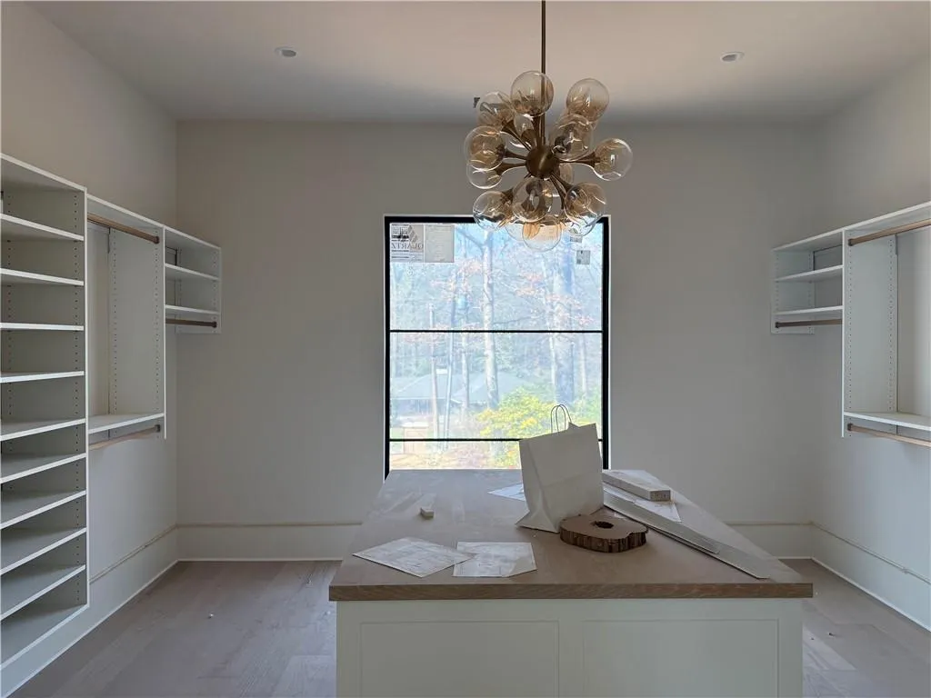 Walk in closet featuring light wood finished floors and a chandelier