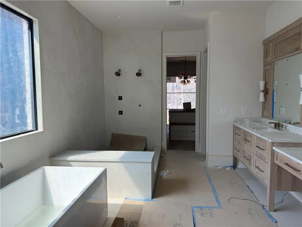 Bathroom featuring a freestanding tub, vanity, walk in shower, and suspended lighting