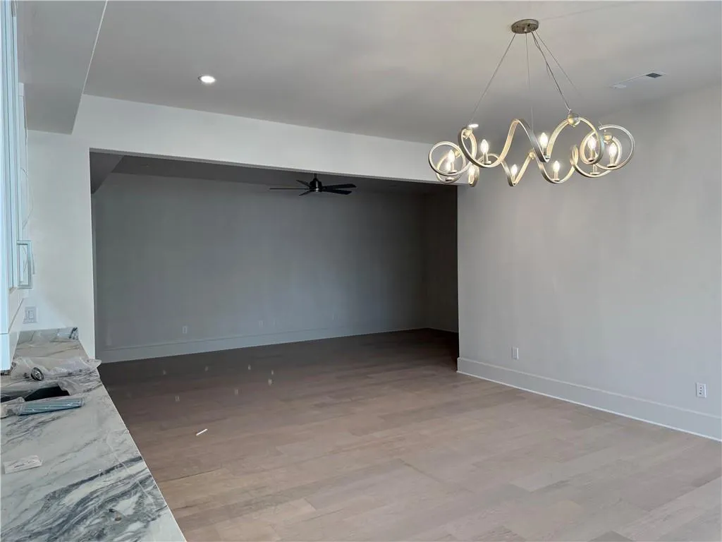 Unfurnished dining area with a ceiling fan, suspended lighting, and light wood-style floors