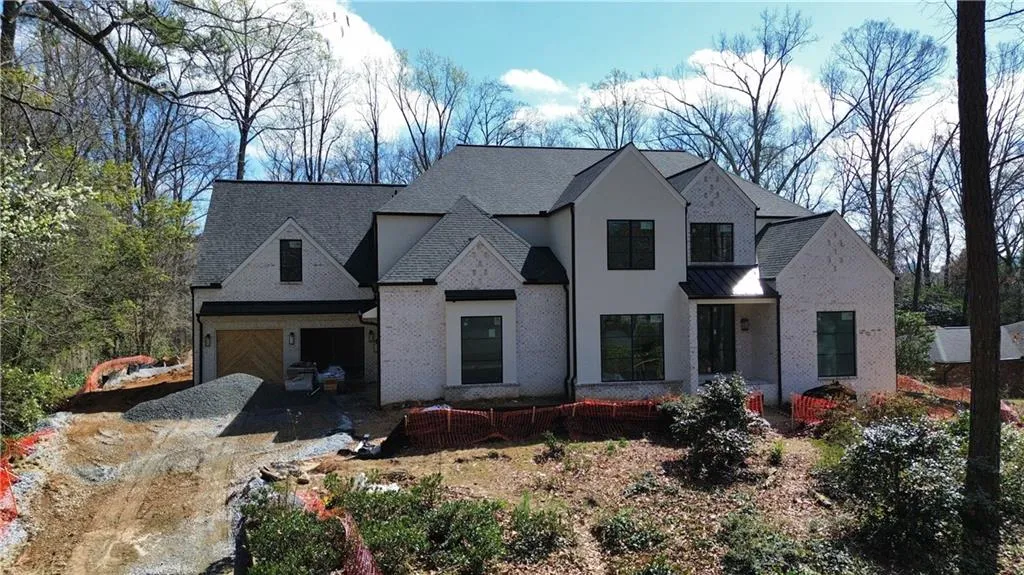 View of front of home featuring driveway, brick siding, a standing seam roof, and roof with shingles