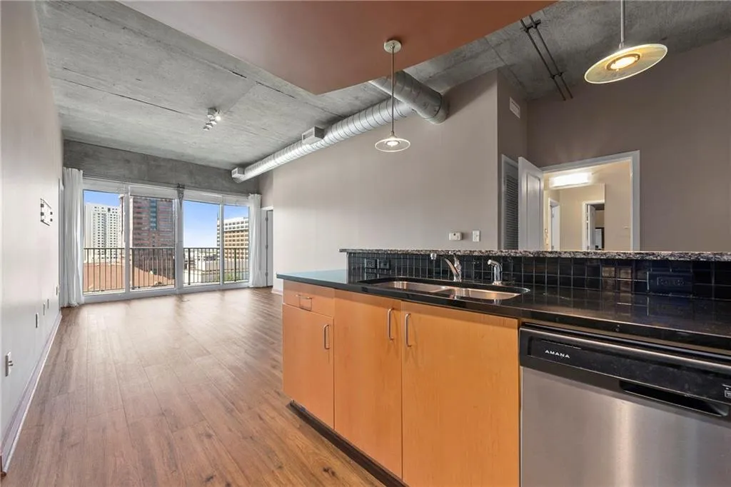 Kitchen featuring stainless steel dishwasher, a sink, light wood-style floors, decorative light fixtures, and open floor plan