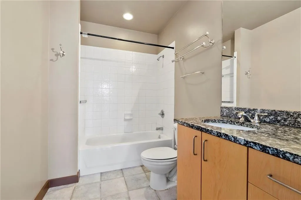 Bathroom featuring toilet, vanity, bathing tub / shower combination, and baseboards
