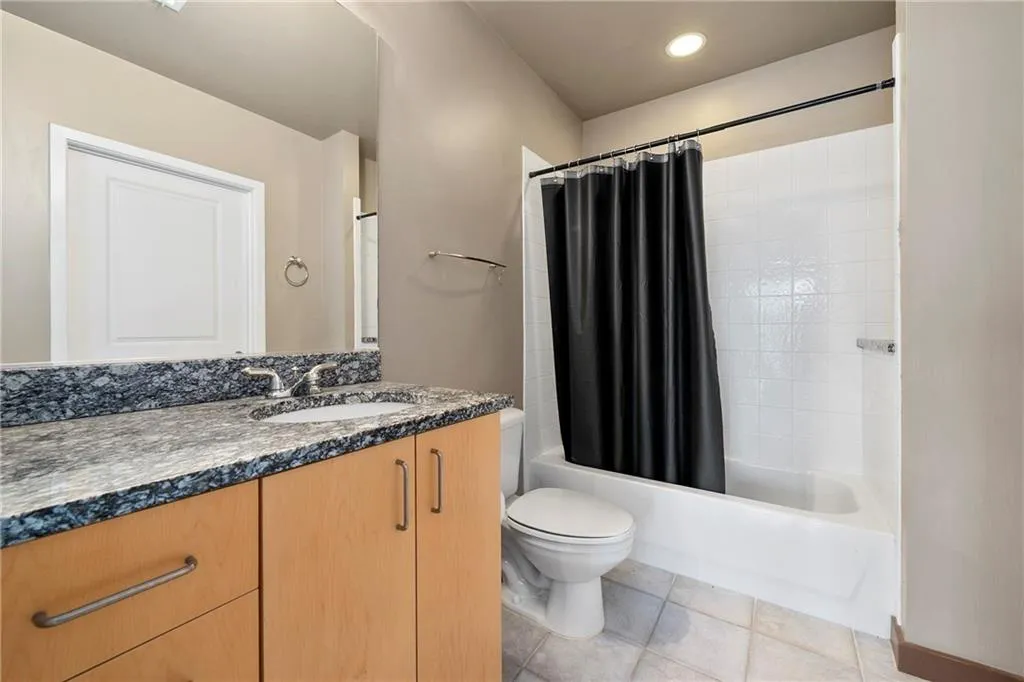 Bathroom with shower / tub combo, toilet, vanity, and tile patterned flooring