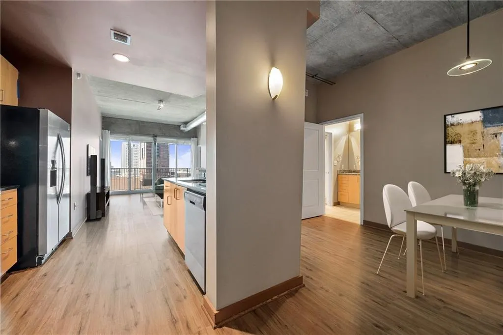 Kitchen with appliances with stainless steel finishes, light wood-type flooring, baseboards, decorative light fixtures, and dark countertops