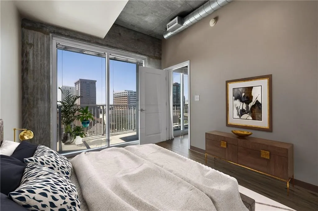 Bedroom with wood finished floors, access to exterior, a city view, a towering ceiling, and baseboards