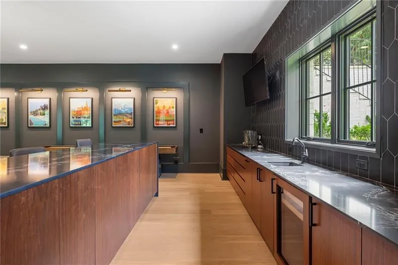 Wet bar featuring a beverage cooler, sink, wood-finish cabinetry, and dark countertop with an elongated hexagonal tile backsplash