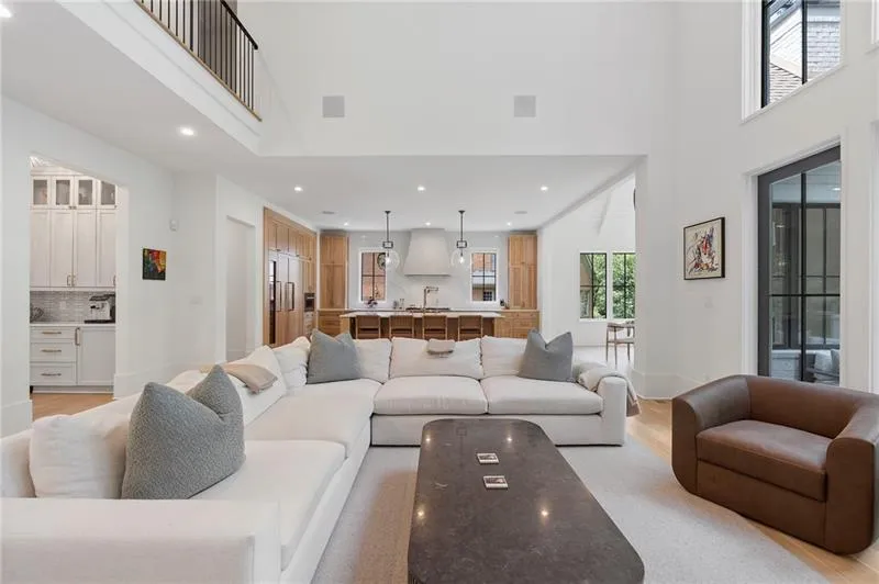 Spacious living area featuring a double-height ceiling and light wood-finish flooring