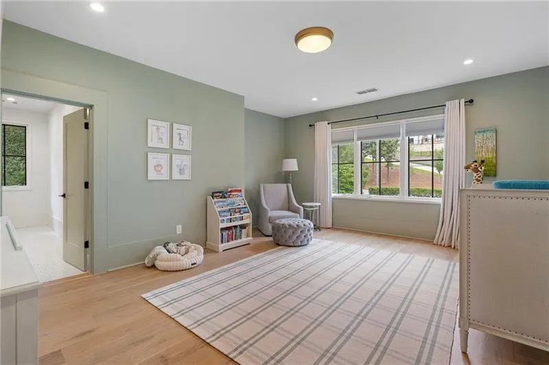Spacious room featuring wood-finish flooring, recessed lighting, and a large multi-pane window with white drapery