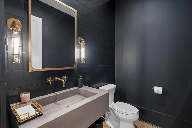 Powder room featuring a rectangular vessel sink, wall-mounted faucet, and brass-framed mirror