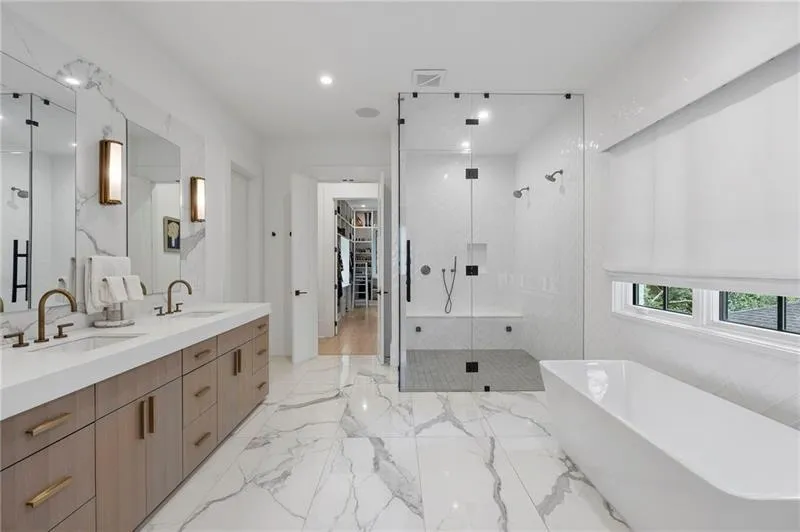 Contemporary bathroom featuring marble-look floor and wall tile, a freestanding bathtub, and a glass-enclosed shower with a built-in bench