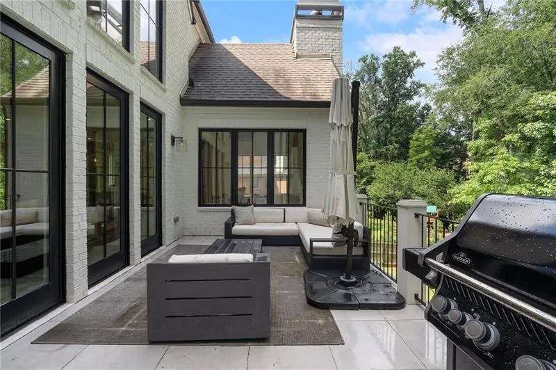 Outdoor patio featuring a white brick exterior, black-framed French doors, and a stone chimney