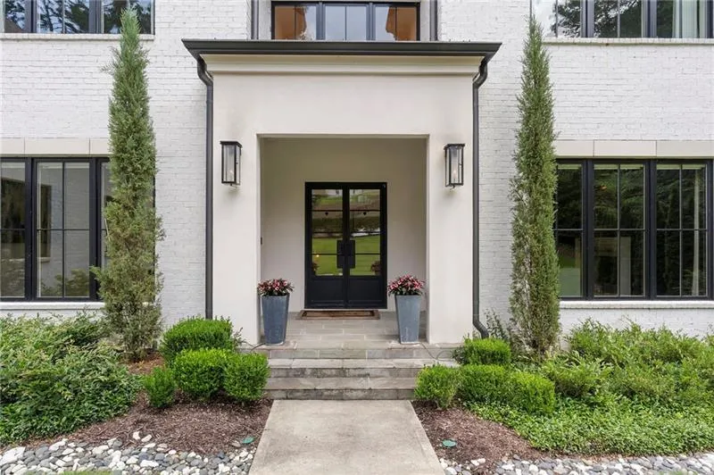 White brick exterior featuring a recessed entry with a light-colored stucco surround