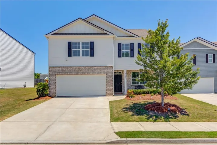 Two-story exterior with a two-car garage, brick and siding facade, covered entry, and manicured landscaping