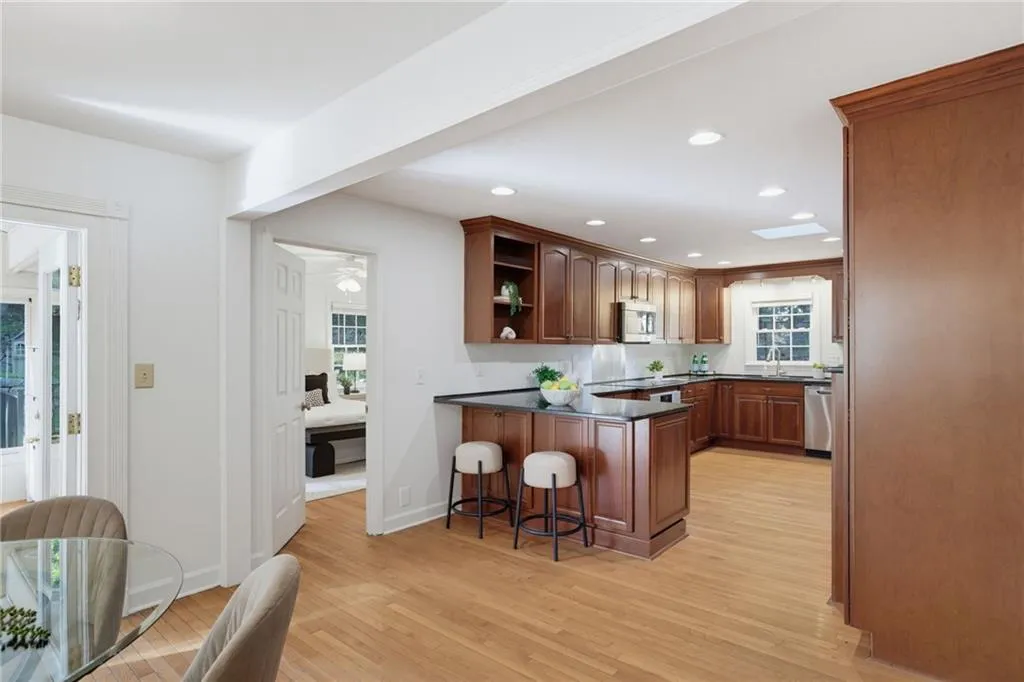 Kitchen featuring wood cabinetry, dark stone countertops, wood-finish flooring, recessed lighting, and a skylight