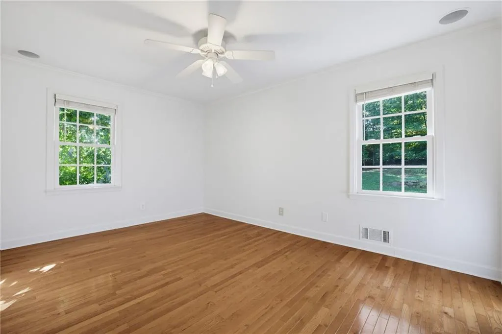 Room featuring wood-finish flooring, dual windows with multi-pane glazing, and a central ceiling fan with an integrated light fixture