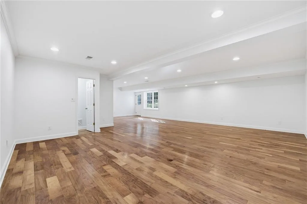 Expansive open-concept interior featuring wood-finish flooring, recessed lighting, and a single-light door