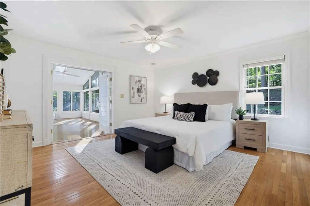 Room featuring wood-finish flooring, multi-pane windows, crown molding, a ceiling fan, and French doors