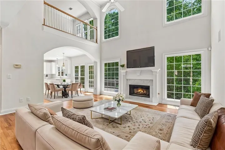 Soaring ceilings with transom windows, a marble-surround fireplace, and wood-finish flooring