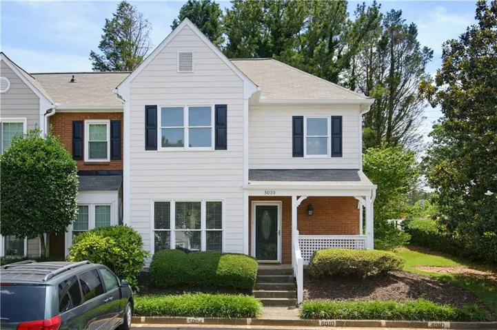 Two-story townhome featuring white siding and brick accents