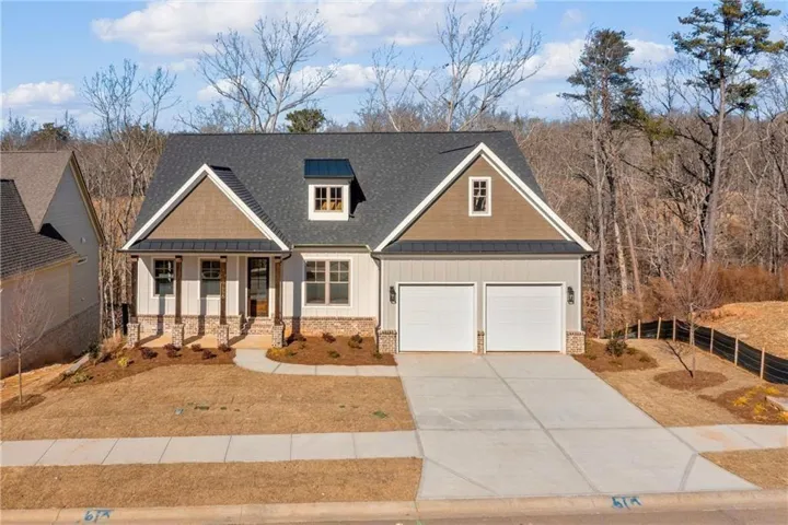 Craftsman-style house featuring board and batten siding, covered porch, a standing seam roof, a metal roof, and concrete driveway