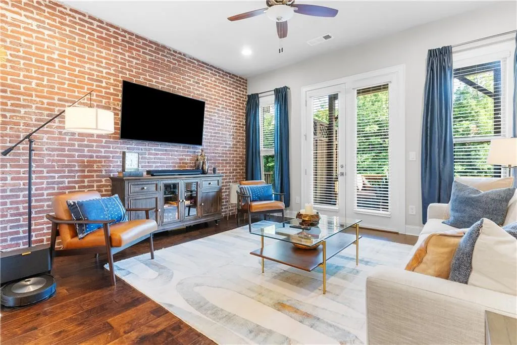 Living room with hardwood / wood-style floors, ceiling fan, and brick wall