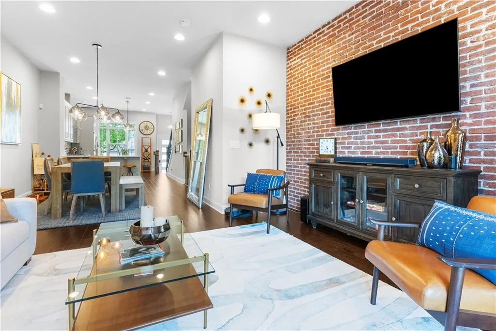 Living room with brick wall and dark hardwood / wood-style floors