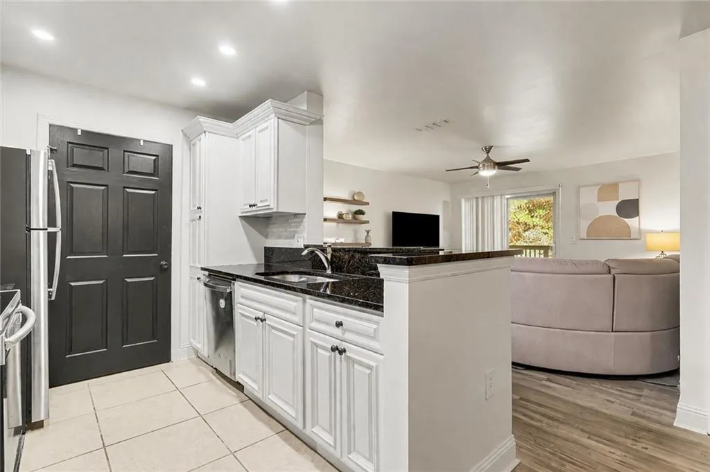 Kitchen featuring dark stone countertops, white cabinets, a peninsula, stainless steel appliances, and open floor plan