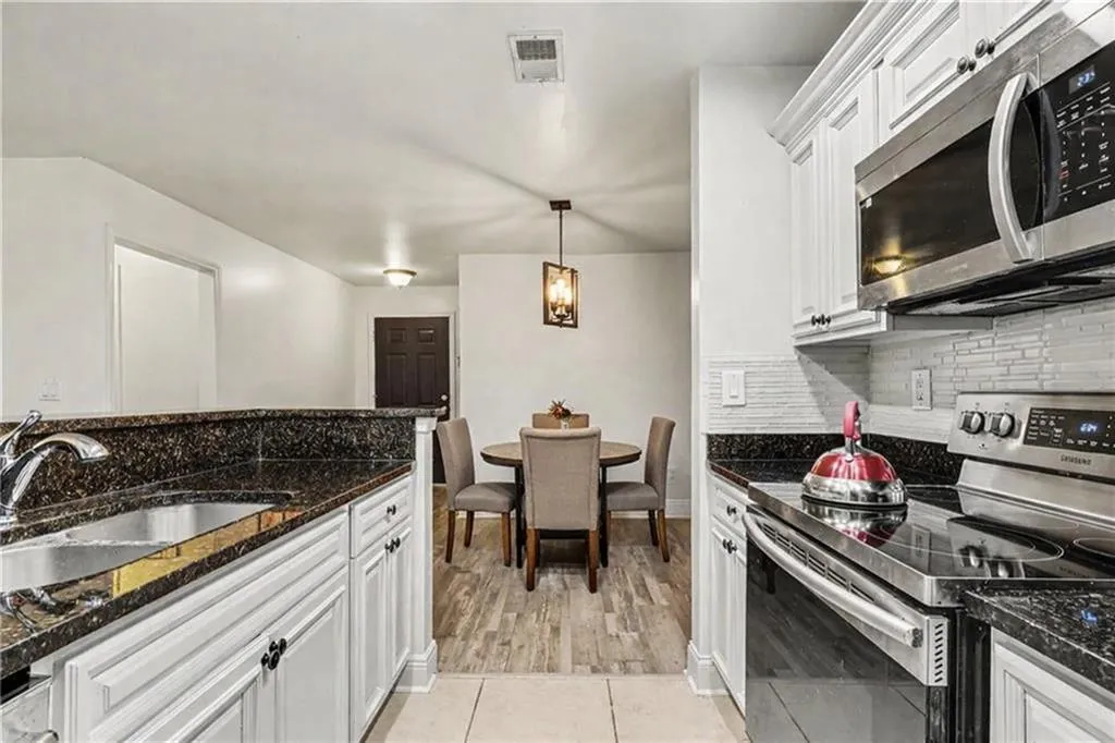 Kitchen featuring stainless steel appliances, dark stone counters, and white cabinets