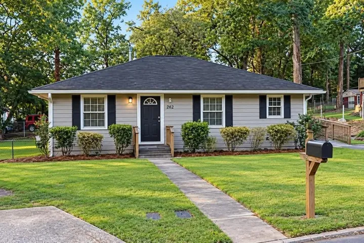 Single-story residence featuring light gray siding with contrasting black shutters and a dark gray shingle roof