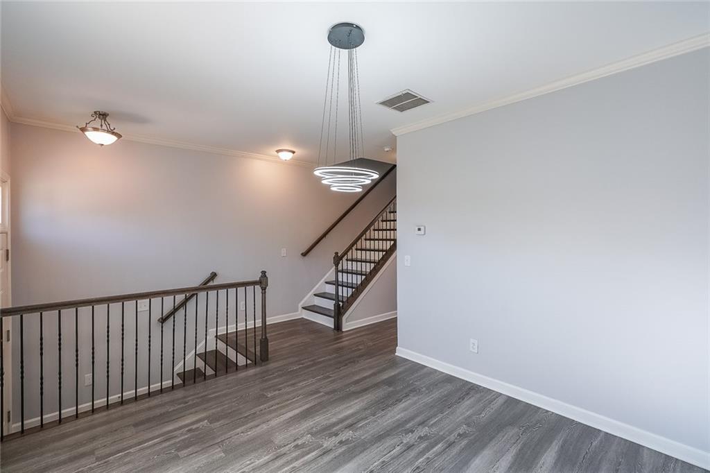 Stairway with dark wood-type flooring and crown molding