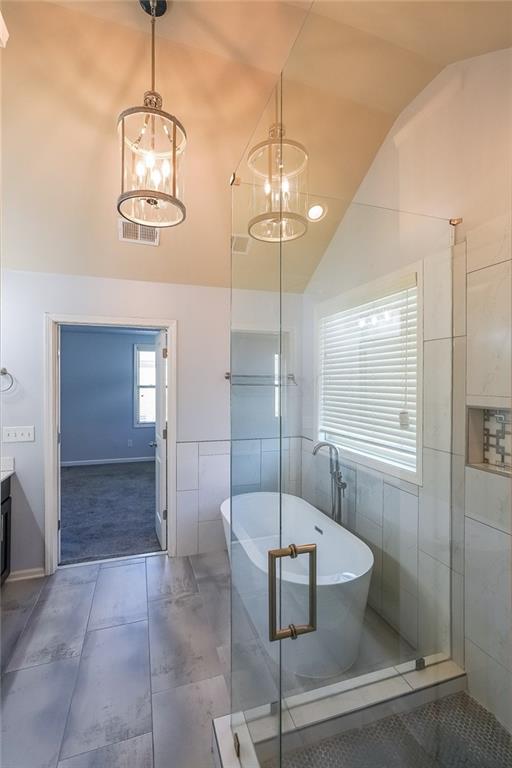 Bathroom with independent shower and bath, vanity, tile walls, tile floors, and vaulted ceiling