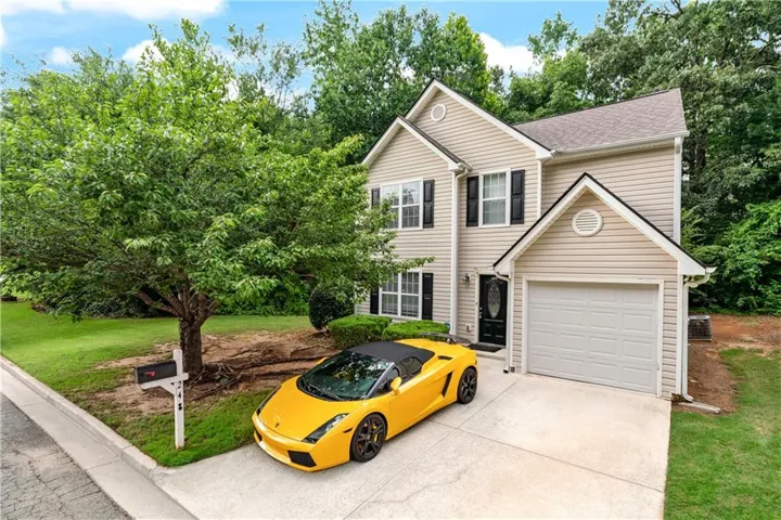 Two-story residence featuring light-colored siding, an attached garage, and a concrete driveway