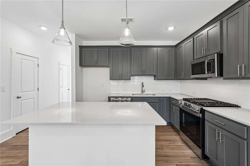 Elevated Kitchen with 42" Gray Cabinets, Quartz Countertops, Pendant Lighting, and Single Bowl Sink