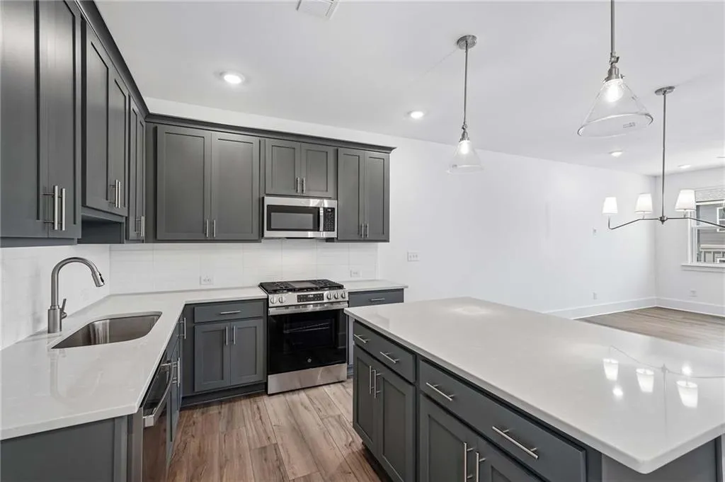 Elevated Kitchen with 42" Gray Cabinets, Quartz Countertops, Pendant Lighting, and Single Bowl Sink