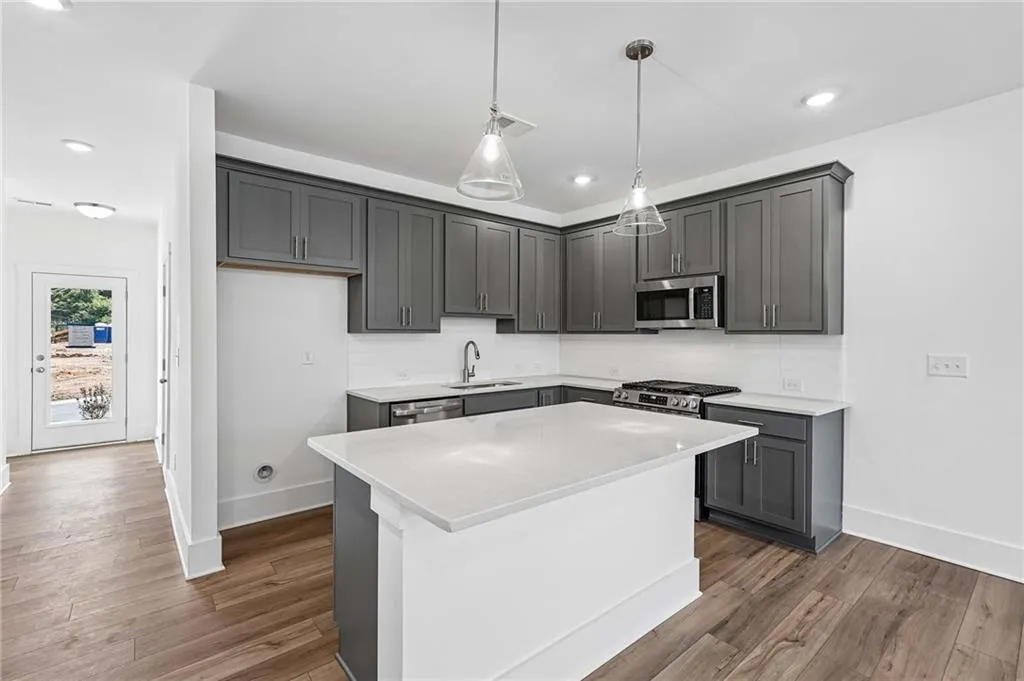 Elevated Kitchen with 42" Gray Cabinets, Quartz Countertops, Pendant Lighting, and Single Bowl Sink