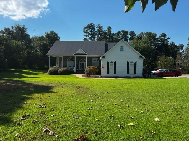 White siding exterior with a dark shingled roof, arched windows, and a covered porch