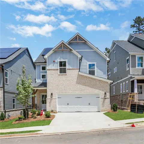 Two-story exterior with light brick and blue siding, featuring a two-car garage, concrete driveway, and front landscaping