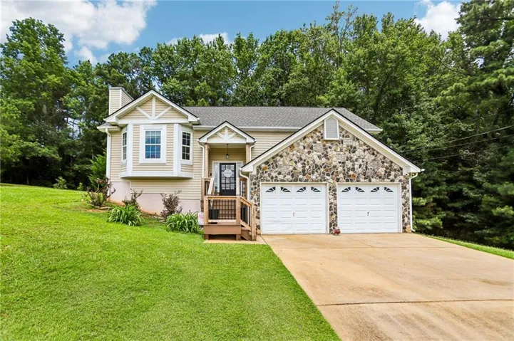 Siding exterior with stone accents, a two-car garage, and a front entry porch with wood railing