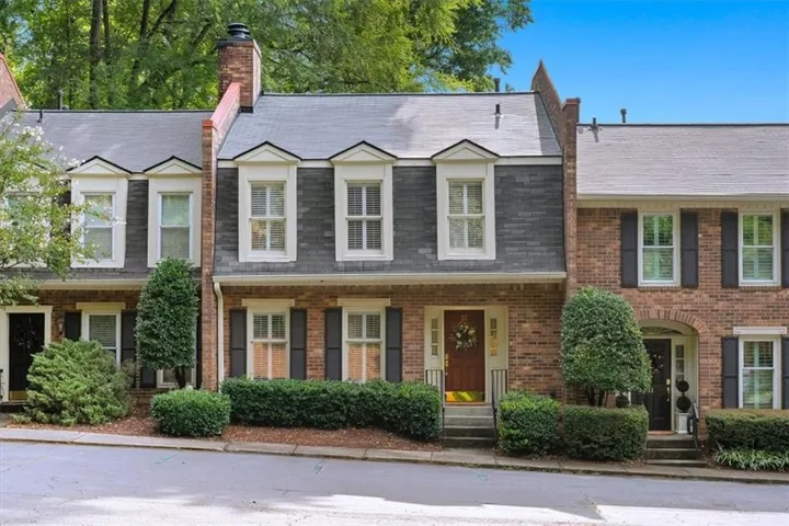 Brick exterior with dark shutters, gable dormers, and a prominent chimney feature