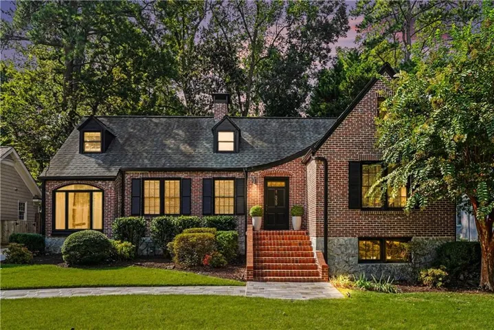 Brick exterior with dark shutters, multiple dormer windows, and a curved architectural element