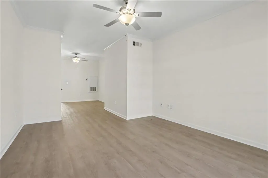 Open-concept layout featuring wood-finish flooring, white walls, and multiple ceiling fans