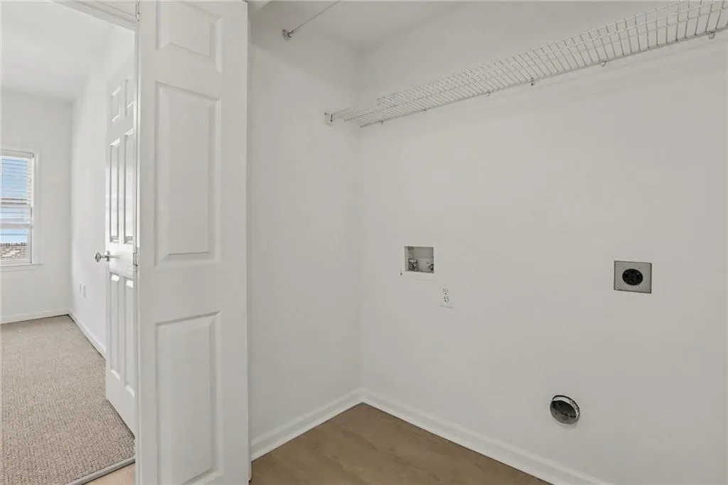 Utility space featuring light wood-finish flooring, white walls, and a wire storage shelf