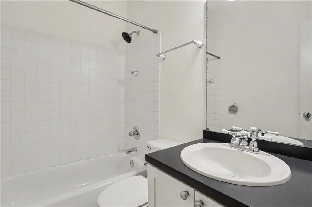 White tiled tub-shower combination with a chrome shower head and faucet