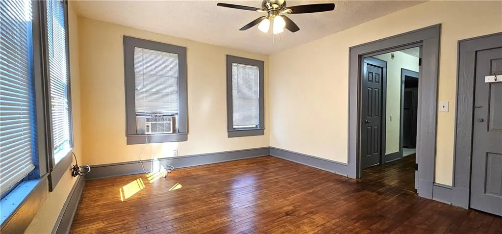 Unfurnished room with hardwood / wood-style flooring, ceiling fan, and baseboards