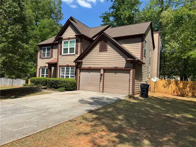 Traditional home with driveway, a shingled roof, and a chimney