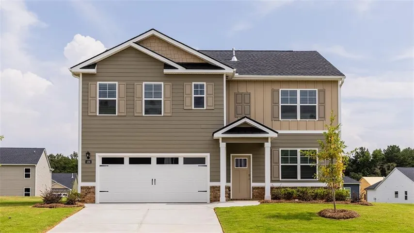 Two-story residence featuring a covered entry, attached garage, and multiple window placements