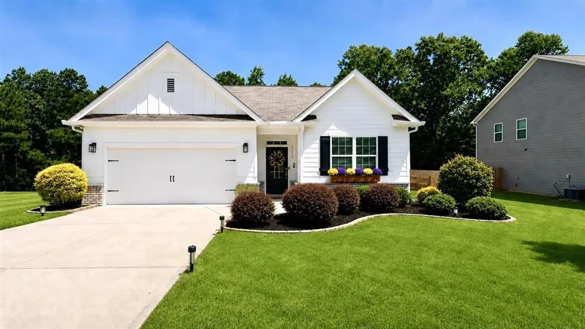 Charming single-story residence showcasing a crisp white exterior with peaked roofline and black-shuttered windows
